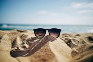 sunglasses-on-sand-by-ocean